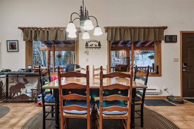 dining room featuring baseboard heating, hardwood / wood-style floors, and a chandelier