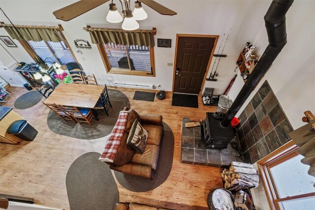 living room featuring hardwood / wood-style floors, a baseboard radiator, a wood stove, and plenty of natural light