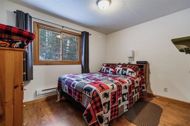 bedroom with hardwood / wood-style flooring and a baseboard heating unit