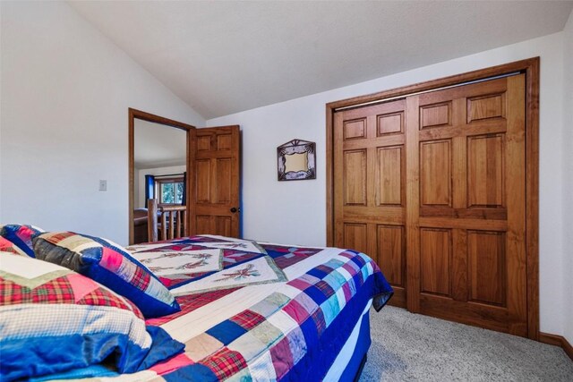 carpeted bedroom with a closet and lofted ceiling