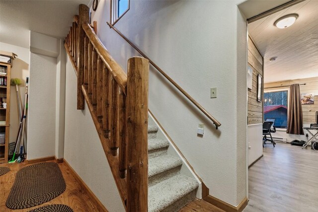 staircase with hardwood / wood-style flooring and wood walls