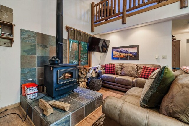 living room featuring hardwood / wood-style flooring, a wood stove, and a high ceiling