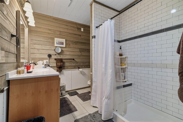 bathroom with vanity, wood walls, tile patterned floors, toilet, and curtained shower