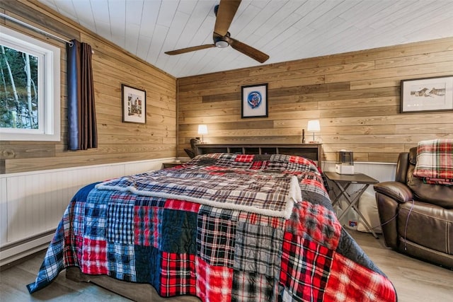 bedroom featuring a baseboard radiator, ceiling fan, and wooden walls