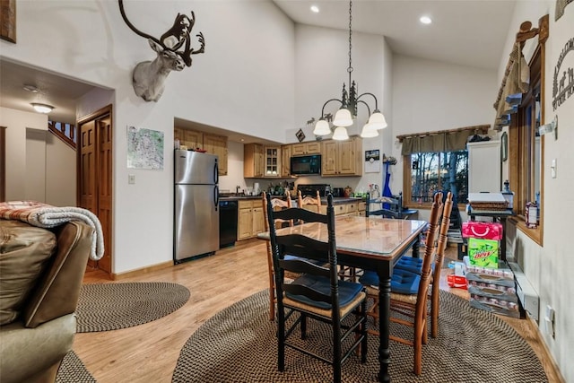 dining room featuring an inviting chandelier, high vaulted ceiling, and light hardwood / wood-style flooring