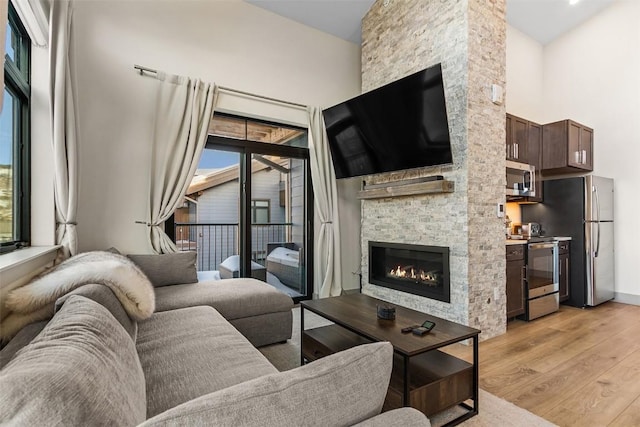 living room with light hardwood / wood-style floors, a towering ceiling, and a fireplace