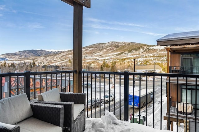 snow covered back of property featuring a mountain view