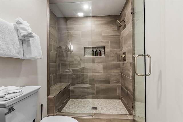 bathroom featuring toilet and a shower with shower door