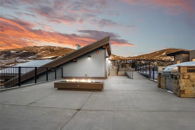 snow covered property with a mountain view, a patio, and an outdoor fire pit