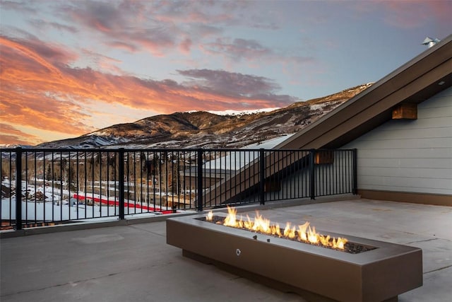 snow covered patio featuring a mountain view and an outdoor fire pit