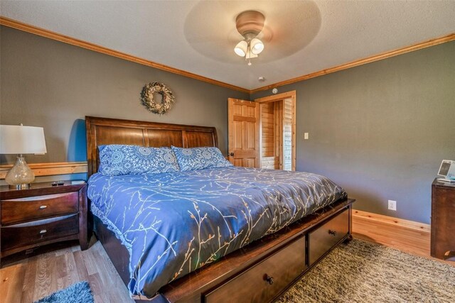 bedroom featuring baseboards, crown molding, a ceiling fan, and wood finished floors