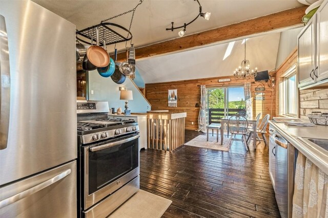 kitchen with hardwood / wood-style floors, appliances with stainless steel finishes, wood walls, an inviting chandelier, and vaulted ceiling with beams