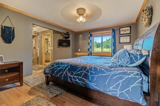 bedroom with ornamental molding, a textured ceiling, wood finished floors, connected bathroom, and ceiling fan