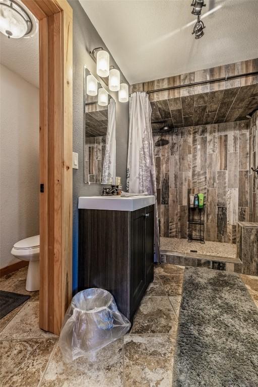 bathroom featuring a tile shower, toilet, and vanity