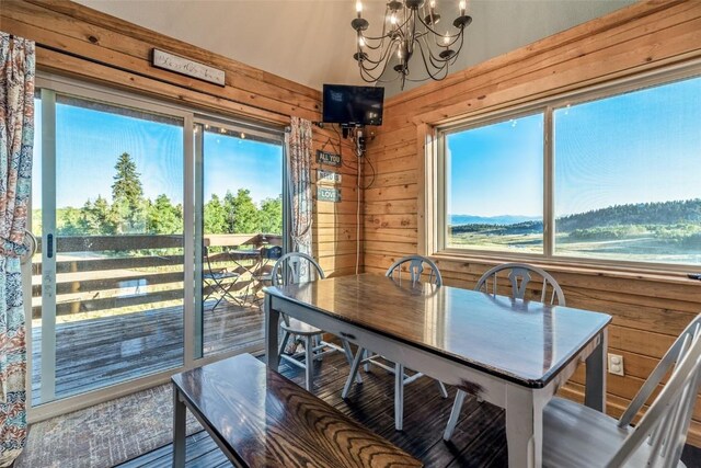 dining space with wooden walls, a notable chandelier, and wood finished floors