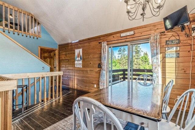 dining area featuring an inviting chandelier, wooden walls, wood finished floors, and high vaulted ceiling