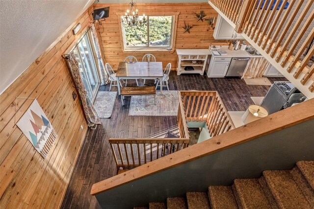 stairway with a notable chandelier, wooden walls, and wood finished floors