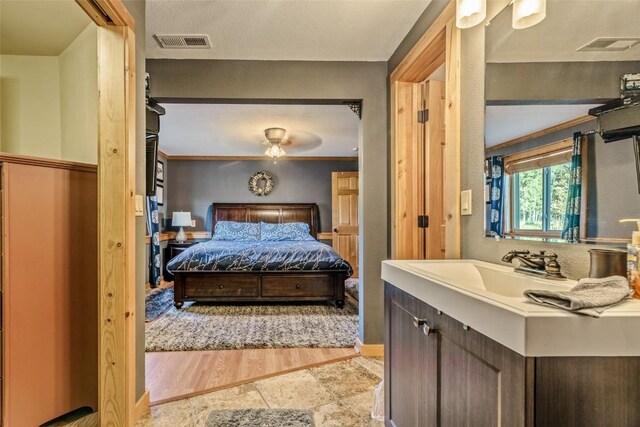 bedroom with a ceiling fan, wood finished floors, visible vents, and a sink