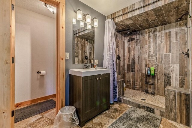 full bathroom with vanity, a tile shower, and stone finish flooring