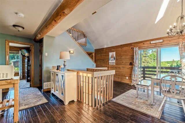 stairway with a wealth of natural light, a chandelier, wood finished floors, and wood walls