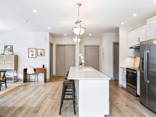 kitchen featuring sink, hanging light fixtures, a center island with sink, white cabinets, and appliances with stainless steel finishes