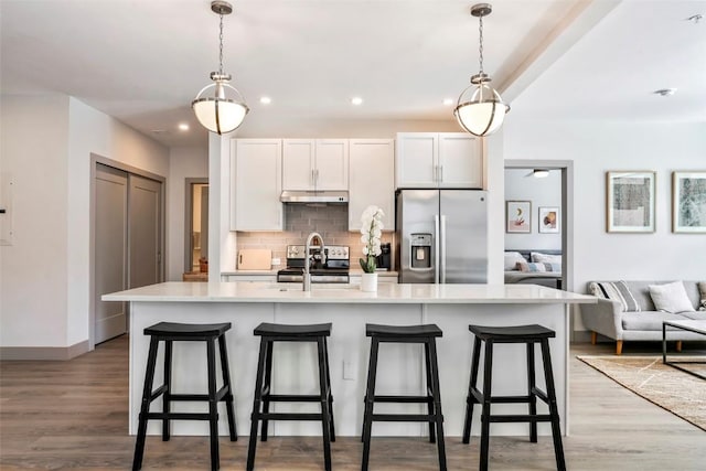 kitchen with white cabinetry, a center island with sink, pendant lighting, and appliances with stainless steel finishes