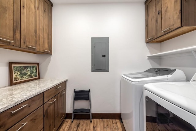 washroom featuring baseboards, electric panel, light wood-style flooring, cabinet space, and separate washer and dryer