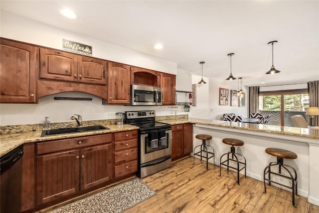 kitchen featuring a sink, light wood-style flooring, appliances with stainless steel finishes, and a breakfast bar area