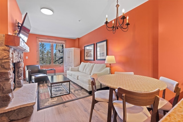 living area featuring a notable chandelier, a fireplace, and wood finished floors