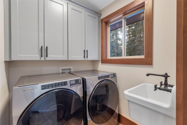 washroom with cabinets, washer and clothes dryer, and sink