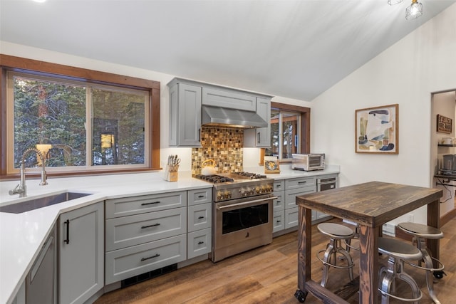 kitchen with sink, gray cabinetry, extractor fan, high end stainless steel range, and light wood-type flooring