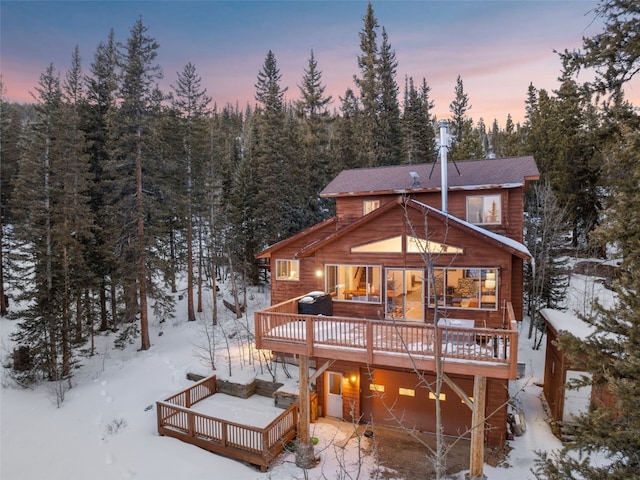 snow covered back of property with a deck