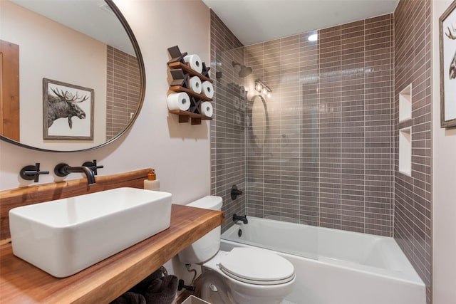 full bathroom featuring sink, tiled shower / bath combo, and toilet