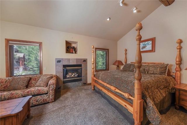 bedroom featuring a tiled fireplace, vaulted ceiling, and carpet