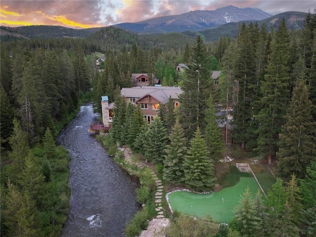 aerial view at dusk featuring a mountain view and a wooded view