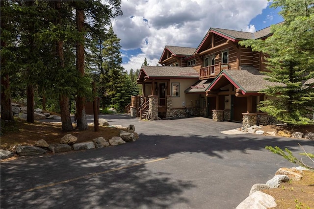 view of front of property featuring a balcony, driveway, and a shingled roof