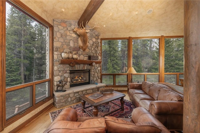 living room with a stone fireplace and wood finished floors