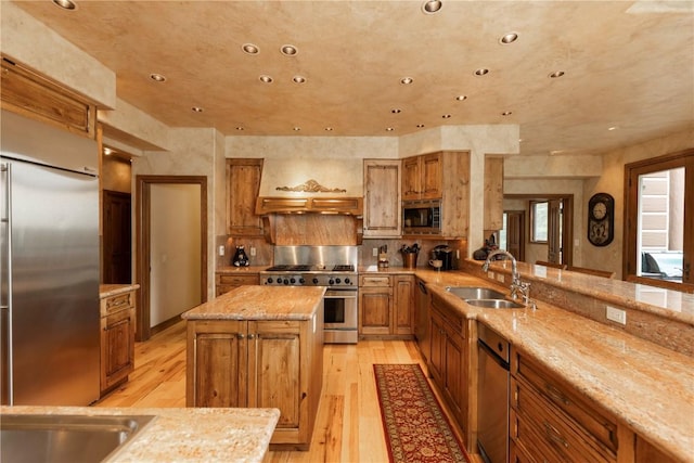 kitchen with light wood finished floors, brown cabinetry, built in appliances, and a sink