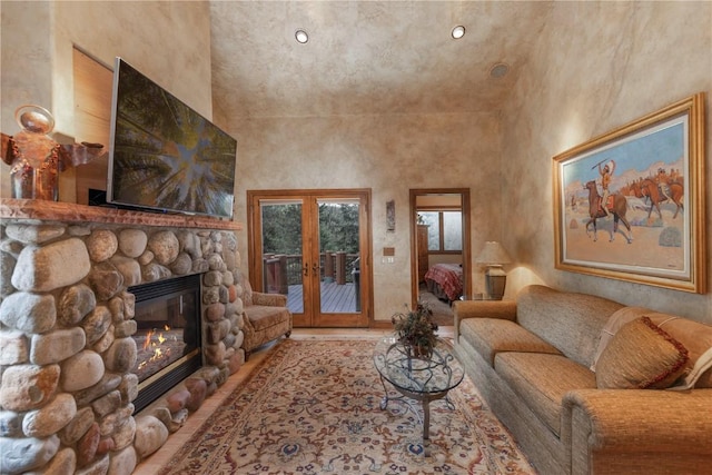 living area with a towering ceiling, a fireplace, and french doors