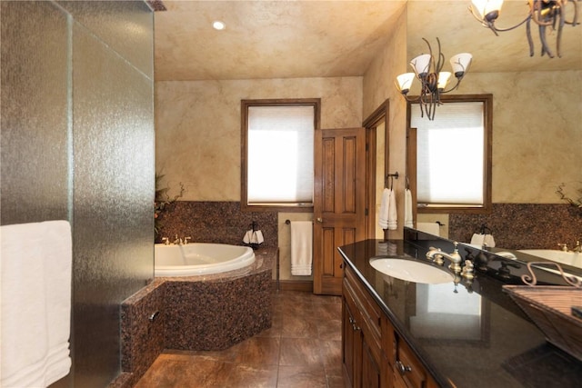 bathroom with vanity, a bath, and a chandelier