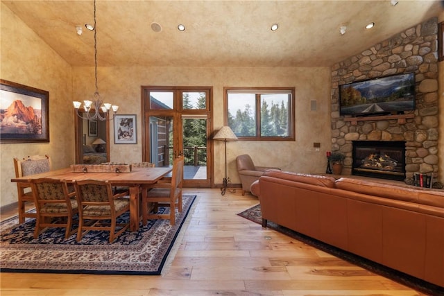 dining area with light wood-style flooring, recessed lighting, french doors, a stone fireplace, and vaulted ceiling