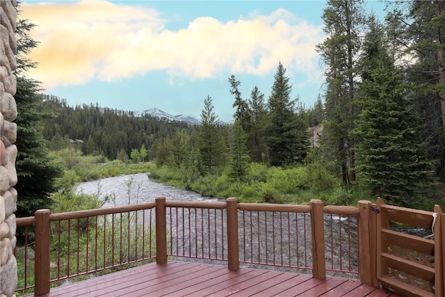 wooden deck featuring a forest view and a water view