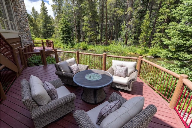 wooden deck with a wooded view and an outdoor living space with a fire pit