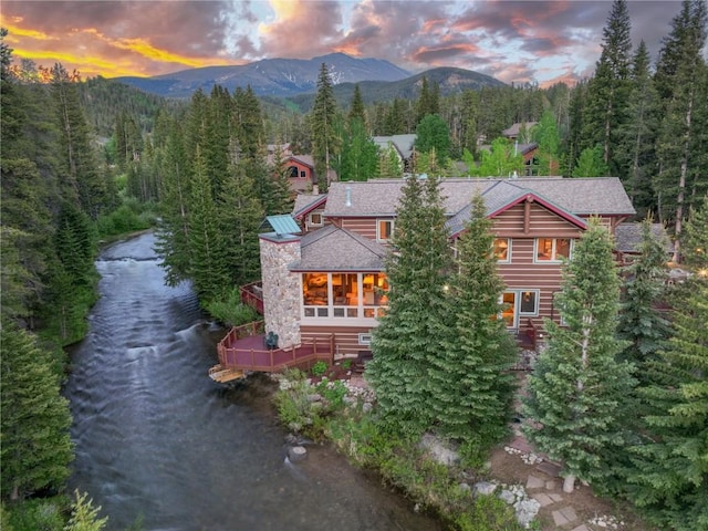 exterior space featuring a forest view, a water and mountain view, and driveway