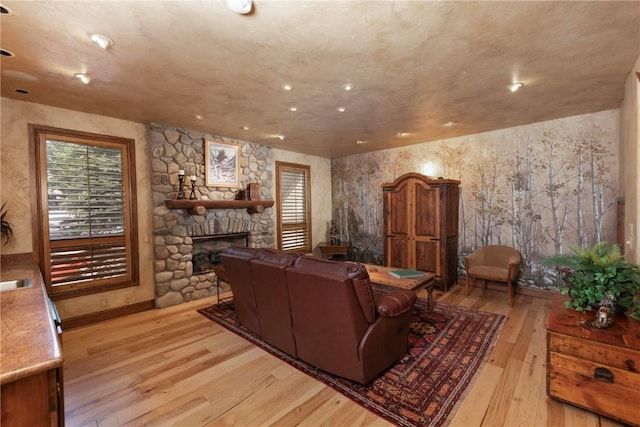 living area featuring a stone fireplace, recessed lighting, and wood finished floors