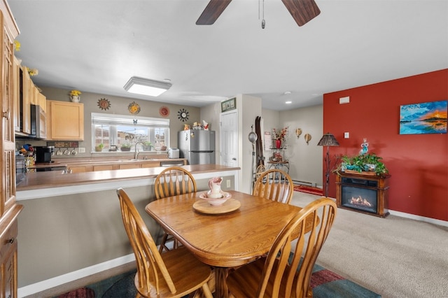 dining space featuring ceiling fan, sink, and light carpet