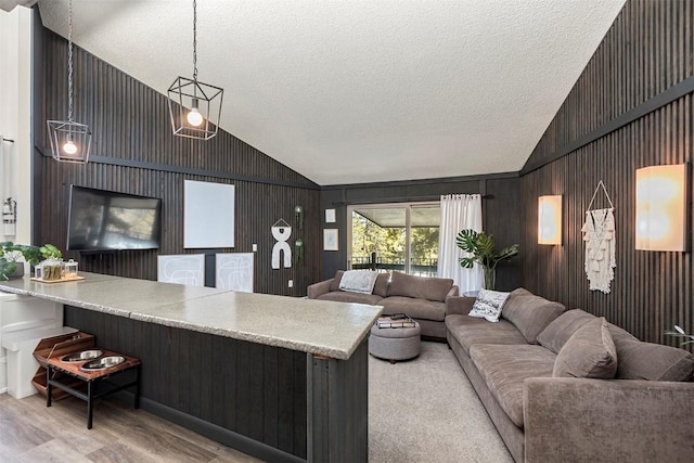 living room featuring high vaulted ceiling, light hardwood / wood-style floors, and a textured ceiling