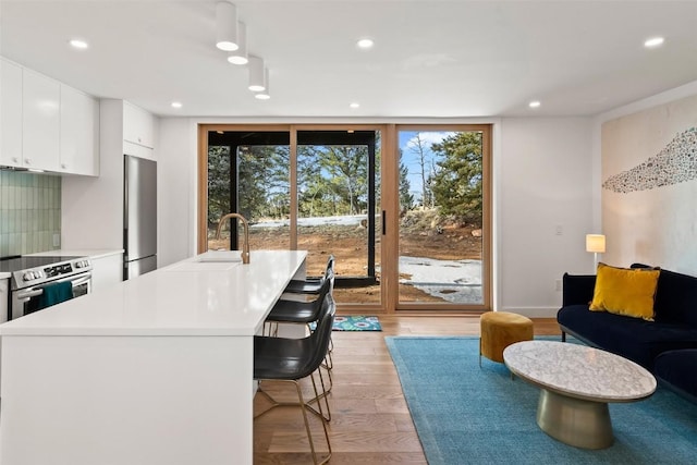 interior space featuring a breakfast bar, sink, light hardwood / wood-style flooring, tasteful backsplash, and stainless steel appliances