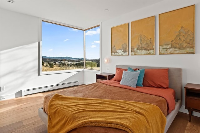 bedroom featuring a mountain view, hardwood / wood-style flooring, and baseboard heating