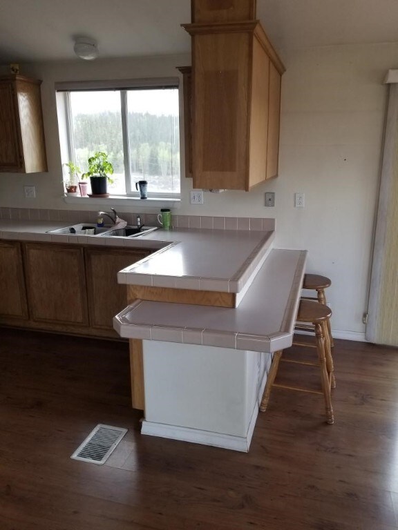 kitchen featuring kitchen peninsula, tile countertops, sink, and dark hardwood / wood-style floors